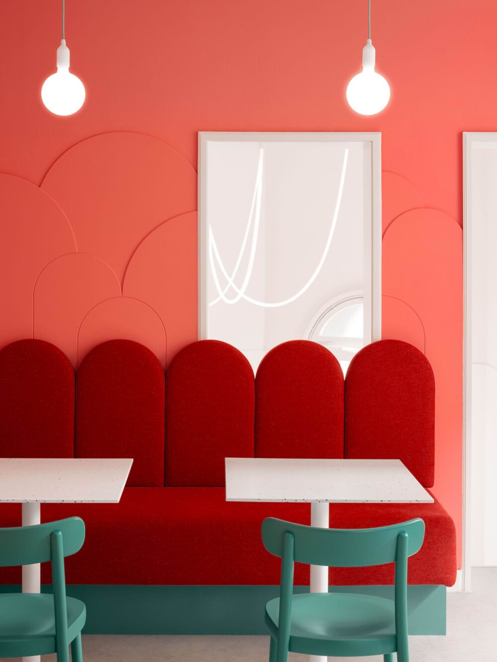 Individueller Bau von Sitzmöbeln: Die durchgehende, fest installierte Sitzbank mit Muschel-Rückenlehne. Das Interieur-Design von 'Hans liebt Kuchen' in Stuttgart setzt auf Sonderanfertigungen und eine starke Farbcodierung